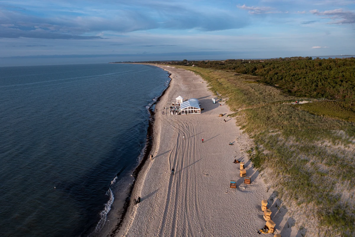 Luftaufnahme vom Strand in Dierhagen mit Hochzeitszelt, Duenen und Ostsee im Abendlicht